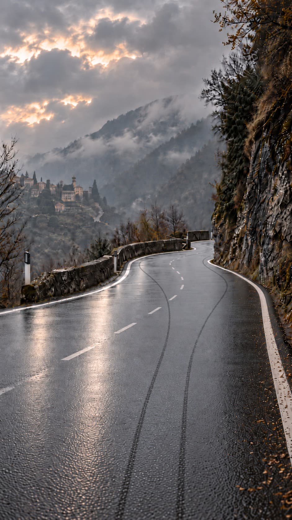 A mountain road winding past a hilltop village at dusk, storm clouds breaking above the valley